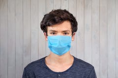 Young man in medical facemask looking at camera. Coronavirus, covid-19 outbreak. Brown eyes of 15 years old boy in mask. Virus,