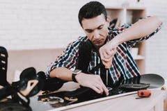 Young Man in Shirt Repairing Snowboard at Home. Man and Hobby. White Room. Engineer with Tool. Young Man at Home. Equipment for Winter. Extreme Hobby. Modern Stock Photo Young Man in Shirt Repairing Snowboard at Home. Man and Hobby. White Room. Engineer with Tool. Young Man at Home. Equipment for Winter. Extreme Hobby. Modern Stock Photo