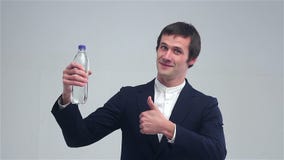 Young man showing a bottle of water and shows great stock video Young man showing a bottle of water and shows great stock video