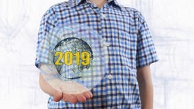 Young man shows a hologram of the planet Earth and text 2019 royalty free stock photo Young man shows a hologram of the planet Earth and text 2019 royalty free stock photo