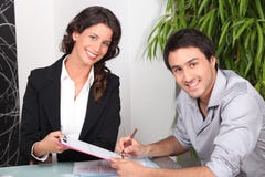 Young man signing document and young woman smiling