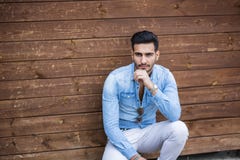 Young man sitting against wood wall stock photography Young man sitting against wood wall stock photography