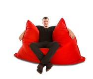 Young man sitting on big red beanbag sofa chair isolated on whit royalty free stock photography Young man sitting on big red beanbag sofa chair isolated on whit royalty free stock photography