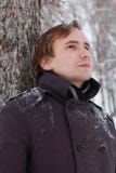 Young man with snowflakes in hair stands near tree Stock Photos Young man with snowflakes in hair stands near tree Stock Photos