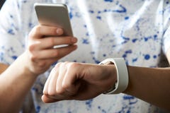 Young Man Synchronizing Smart Watch With Mobile Phone royalty free stock image Young Man Synchronizing Smart Watch With Mobile Phone royalty free stock image