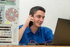 Young man technician working on broken computer and call the customer royalty free stock image Young man technician working on broken computer and call the customer royalty free stock image