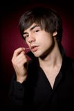 Young man with toothpick in black shirt. Young passional man with toothpick in black shirt on red background with candles Stock Photo Young man with toothpick in black shirt. Young passional man with toothpick in black shirt on red background with candles Stock Photo