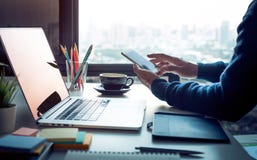 Young man using smartphone with modern work table and computer laptop and cityscapes view from window.Business concepts ideas. stock photography Young man using smartphone with modern work table and computer laptop and cityscapes view from window.Business concepts ideas. stock photography