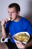 Young man watching soccer on tv at home and eating chips stock images Young man watching soccer on tv at home and eating chips stock images