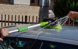 Young men washing silver car with pressured water and brush at sunny day. Close up of cleaning car on summer time Stock Images Young men washing silver car with pressured water and brush at sunny day. Close up of cleaning car on summer time Stock Images