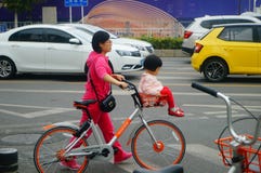 Young mother with a bicycle basket carrying the little girl in the street Royalty Free Stock Images Young mother with a bicycle basket carrying the little girl in the street Royalty Free Stock Images