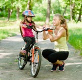 Young mother praises her daughter, who learned to ride a bike stock photography Young mother praises her daughter, who learned to ride a bike stock photography