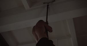 Young muscular athletic Caucasian man climbing rope, doing hardcore functional workout training in large gym slow motion