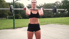 Young muscular woman is doing exercises with the barbell