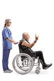Young nurse with a mature male patient making a rock and roll hand sign in wheelchair stock image Young nurse with a mature male patient making a rock and roll hand sign in wheelchair stock image