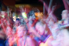Young people crowd dancing and cheering during a rock band music concert performance at a festival