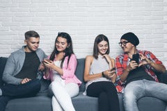 Young friends people looking down at cellular phone. Sitting on the couch and ignoring each others with on the smart phones. royalty free stock photo Young friends people looking down at cellular phone. Sitting on the couch and ignoring each others with on the smart phones. royalty free stock photo