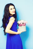 Sexy girl with roses on blue. Young pretty sexy woman or girl with cute smiling face and long brunette hair has fashionable makeup with red lipstick in blue stock image Sexy girl with roses on blue. Young pretty sexy woman or girl with cute smiling face and long brunette hair has fashionable makeup with red lipstick in blue stock image