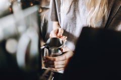A young pretty slim girl,wearing casual outfit,is cooking coffee in a modern coffee shop. It focuses on the process. royalty free stock photo A young pretty slim girl,wearing casual outfit,is cooking coffee in a modern coffee shop. It focuses on the process. royalty free stock photo