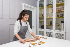 Young pretty woman prepares the dough and bakes gingerbread and cookies in the kitchen. Merry Christmas and Happy New stock photography Young pretty woman prepares the dough and bakes gingerbread and cookies in the kitchen. Merry Christmas and Happy New stock photography