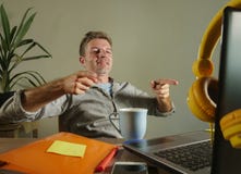 Young satisfied and confident business man leaning on chair happy pointing with fingers to laptop computer sitting at home office Royalty Free Stock Images Young satisfied and confident business man leaning on chair happy pointing with fingers to laptop computer sitting at home office Royalty Free Stock Images