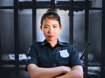 Young serious and attractive Asian Chinese guard woman standing on cell at State penitentiary wearing police uniform in crime stock image Young serious and attractive Asian Chinese guard woman standing on cell at State penitentiary wearing police uniform in crime stock image