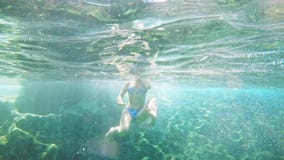 Young girl in bikini swimsuit in the blue Lagoon at sea, underwater shot stock footage Young girl in bikini swimsuit in the blue Lagoon at sea, underwater shot stock footage