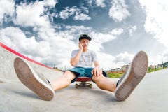 Young Skater Sitting On Skateboard In Park And Talking On Phone Royalty Free Stock Photo