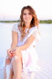 Young smiling female person sitting on white sand and wearing dr stock photography Young smiling female person sitting on white sand and wearing dr stock photography