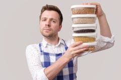 Young smiling man in apron hold several boxes with grains. royalty free stock photo Young smiling man in apron hold several boxes with grains. royalty free stock photo