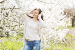 Young smiling relaxed beautiful woman in light casual clothes clinging to headphones listening music in city garden or royalty free stock image Young smiling relaxed beautiful woman in light casual clothes clinging to headphones listening music in city garden or royalty free stock image