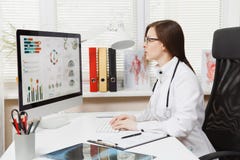 Young woman sitting at desk, working on modern computer with medical documents in light office in hospital. Female stock image Young woman sitting at desk, working on modern computer with medical documents in light office in hospital. Female stock image