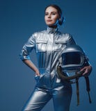 Young spacewoman in silver suit holding helmet
