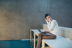 Young Student Or Businesswoman Sitting On Desk In Room In A Library Or Office, Using Laptop. Stock Photography Young Student Or Businesswoman Sitting On Desk In Room In A Library Or Office, Using Laptop. Stock Photography