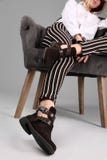 Young stylish woman with trendy shoes sitting in armchair on grey stock photography Young stylish woman with trendy shoes sitting in armchair on grey stock photography