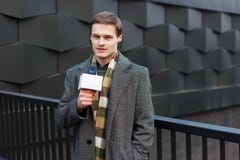 A young stylishly dressed male TV reporter is reporting on the street in the city stock photo A young stylishly dressed male TV reporter is reporting on the street in the city stock photo