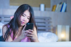 Young sweet and beautiful Asian Chinese 20s or 30s woman smiling happy lying on bed using internet mobile phone dating or sending Stock Photography Young sweet and beautiful Asian Chinese 20s or 30s woman smiling happy lying on bed using internet mobile phone dating or sending Stock Photography
