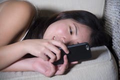 Young Sweet Happy And Pretty Asian Korean Woman Using Internet Social Media App On Mobile Phone Smiling Cheerful Lying On Home Sof Stock Image