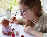 Young teenage girl makes toy, paints clay pig with gouache. Creative leisure for children. Supporting creativity, learning by royalty free stock photography Young teenage girl makes toy, paints clay pig with gouache. Creative leisure for children. Supporting creativity, learning by royalty free stock photography