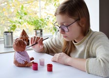 Young teenage girl makes toy, paints clay pig with gouache. Creative leisure for children. Supporting creativity, learning by royalty free stock image Young teenage girl makes toy, paints clay pig with gouache. Creative leisure for children. Supporting creativity, learning by royalty free stock image