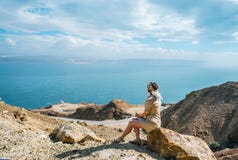 Young tourist woman is sitting on the top of the mounting and looking at a beautiful sea bay landscape stock photos Young tourist woman is sitting on the top of the mounting and looking at a beautiful sea bay landscape stock photos