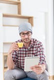 Young trendy man sitting at the office and enjoying his morning coffee while reading news on tablet device royalty free stock image Young trendy man sitting at the office and enjoying his morning coffee while reading news on tablet device royalty free stock image