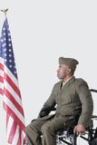 Young US soldier in wheelchair looking at American flag over gray background royalty free stock images Young US soldier in wheelchair looking at American flag over gray background royalty free stock images