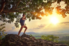Young woman admires the sunset with a backpack standing on cliff stock photo Young woman admires the sunset with a backpack standing on cliff stock photo