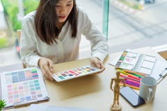 Young woman designer working with color samples for selection on office desk stock photo Young woman designer working with color samples for selection on office desk stock photo