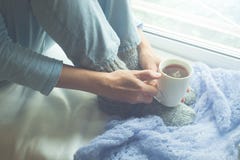 Young Woman Enjoying her morning coffee or tea, Looking Out the Window. Beautiful romantic unrecognizable girl drinking hot drink royalty free stock photography Young Woman Enjoying her morning coffee or tea, Looking Out the Window. Beautiful romantic unrecognizable girl drinking hot drink royalty free stock photography