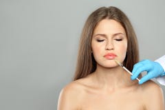 Young woman getting lips injection on grey background, space for text. royalty free stock photography Young woman getting lips injection on grey background, space for text. royalty free stock photography