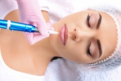 Young woman getting permanent makeup on lips