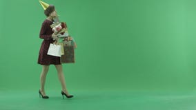 A young woman is going from left side with a lot of gifts on the green screen stock video A young woman is going from left side with a lot of gifts on the green screen stock video