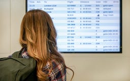 Young woman with green backpack looking at departure board screen at the airport, view from behind stock photos Young woman with green backpack looking at departure board screen at the airport, view from behind stock photos